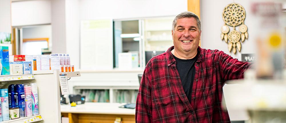 Man standing next to shelves in a pharmacy